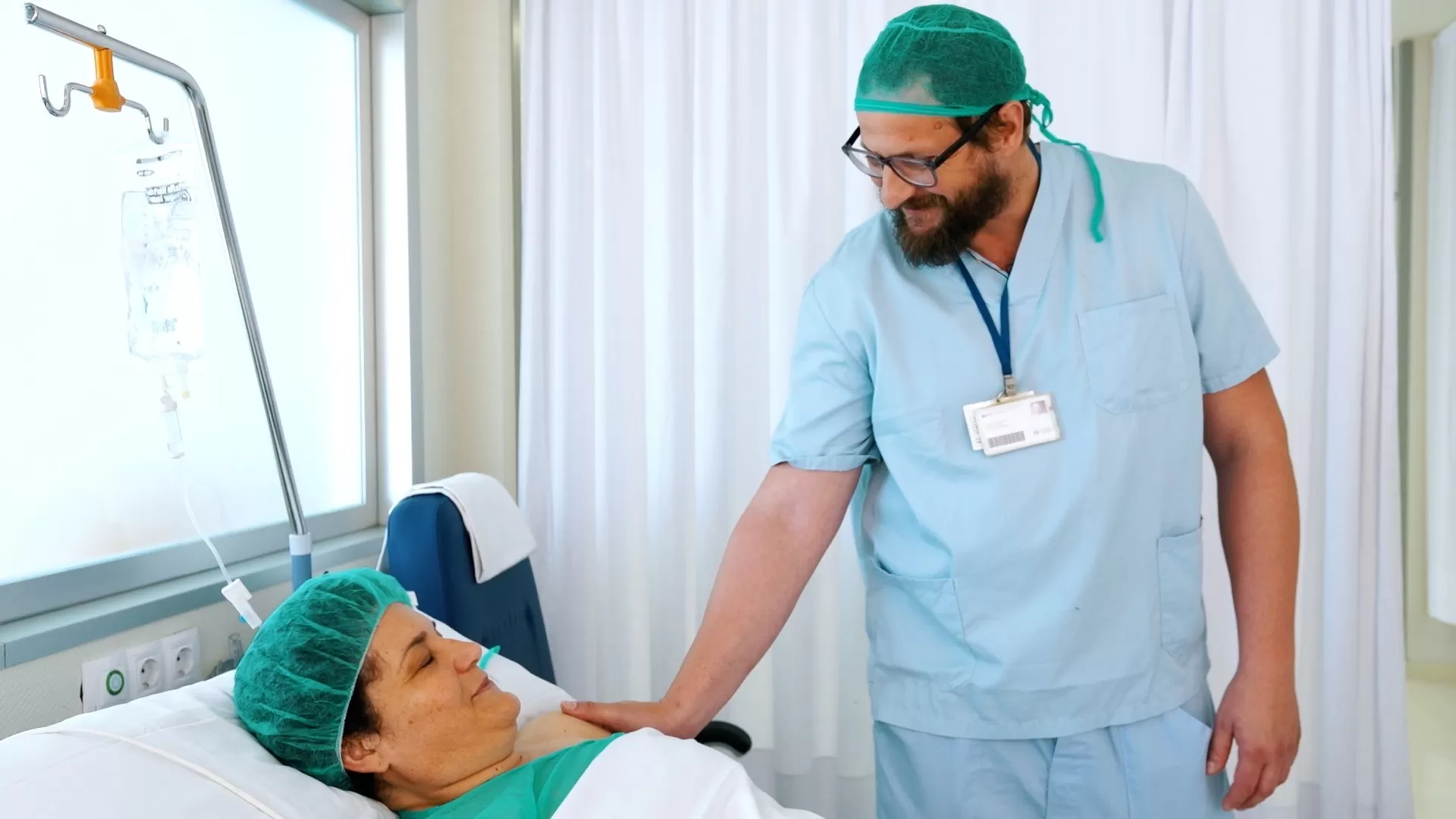 Paciente recuperándose en el postoperatorio, recibiendo atención médica tras una cirugía.